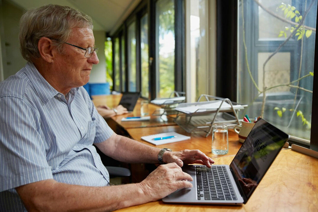 older adult learning coding on laptop
