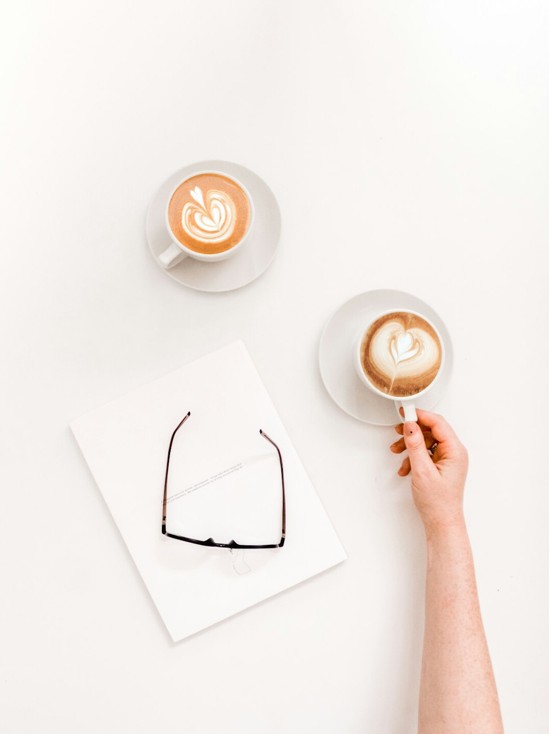 Hands typing on a laptop next to a notebook and coffee cup